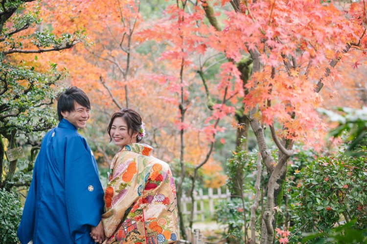 緑の中に紅葉が見られる庭園で楽しそうに振り返る新郎新婦