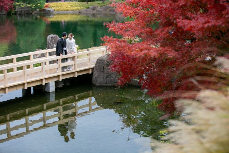 池にかかる橋の上から景色を眺める新郎新婦