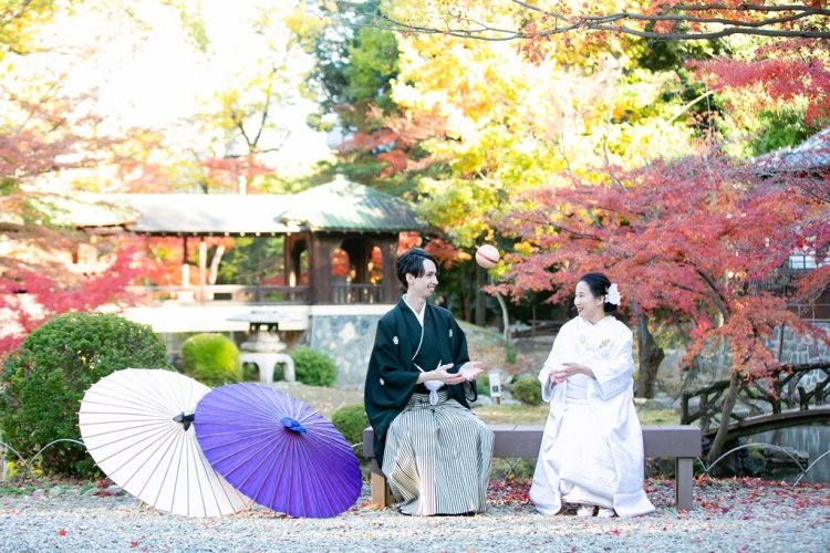 色付く日本庭園で椅子に座り毬で楽しむ新郎新婦